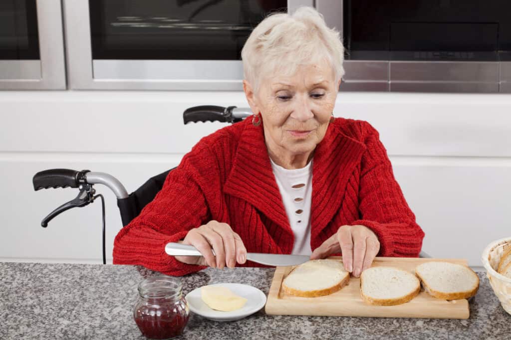 Senior lady making herself a snack of bread butter and jam