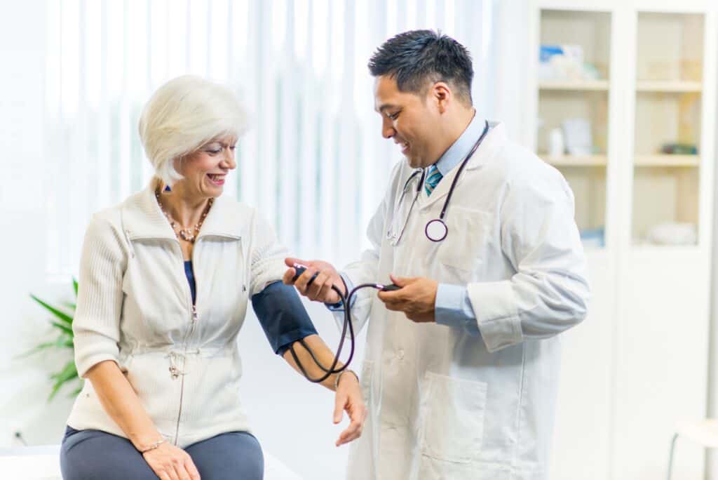 Smiling doctor checking the blood pressure of a smiling senior patient