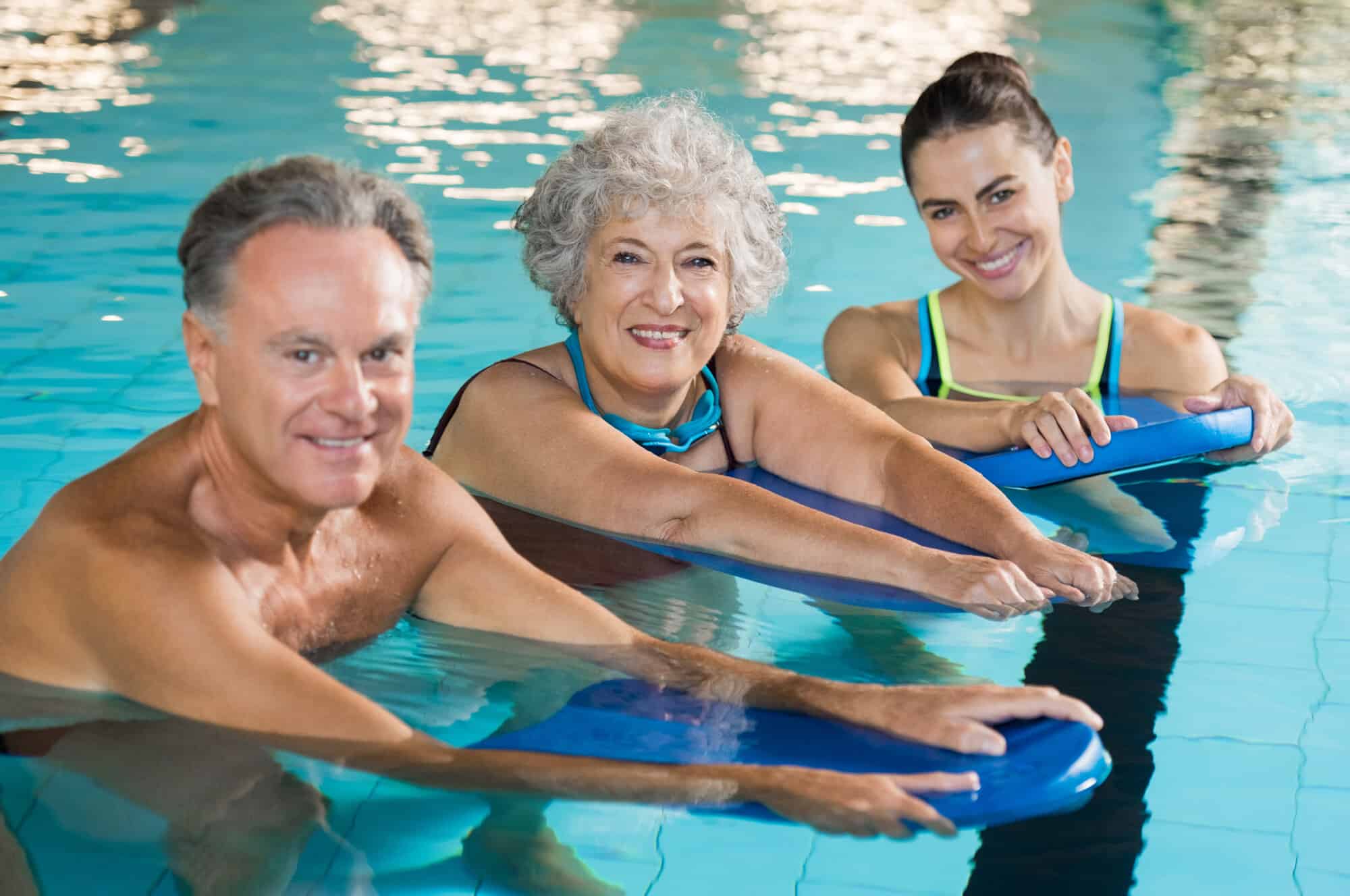 Happy,Senior,Couple,Taking,Swimming,Lessons,From,Young,Trainer.,Smiling